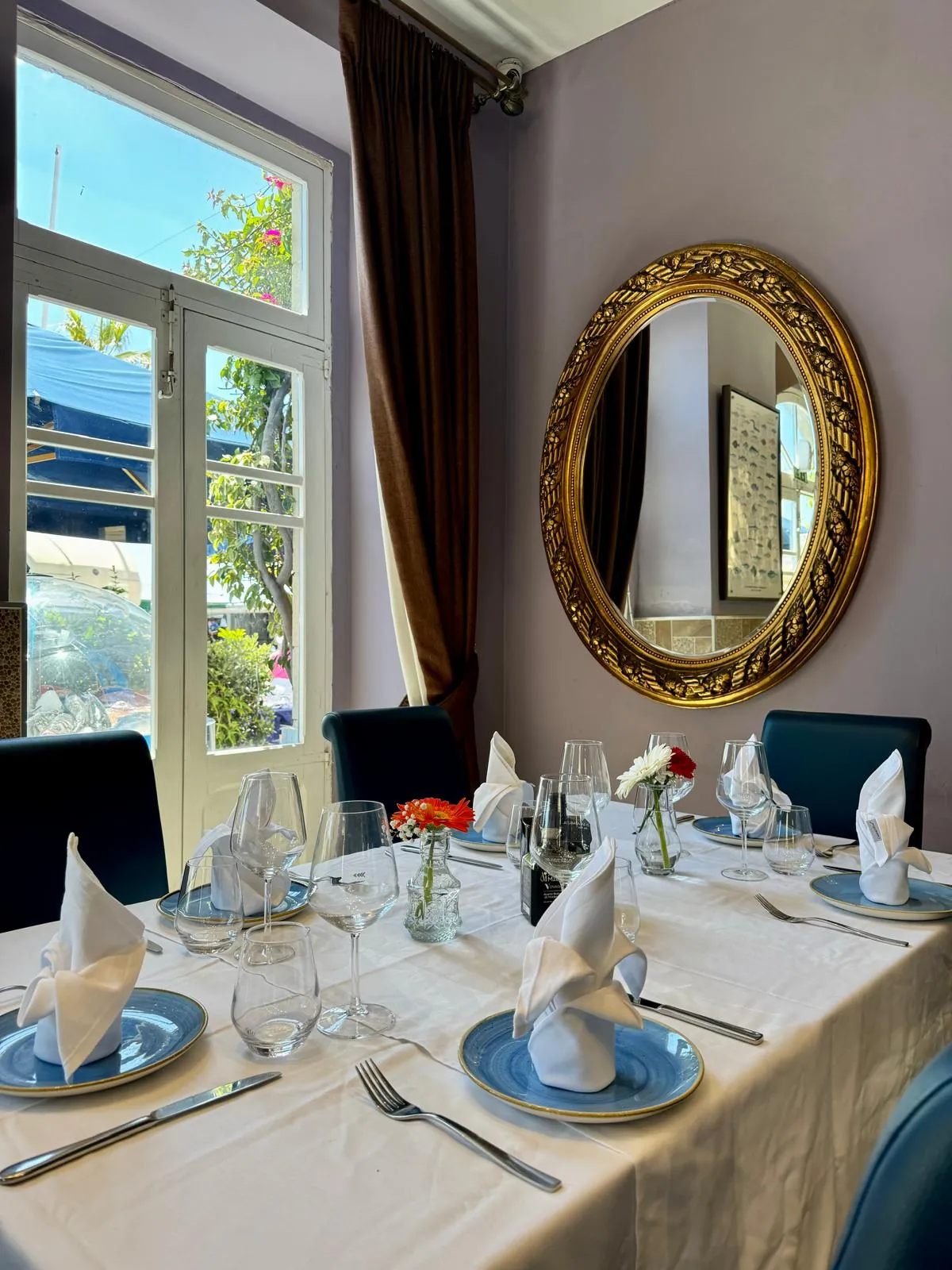 The dining room with a gilded mirror and blue table settings